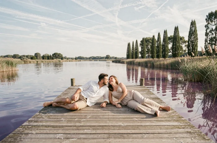 Couple allongé sur un ponton en bois au bord d'un lac calme entouré de roseaux en Camargue lors d'un week-end romantique